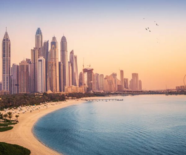 Sunset view of the Dubai Marina and JBR area and the famous Ferris Wheel and golden sand beaches in the Persian Gulf. Holidays and vacations in the UAE